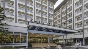 Et moderne hotel med flere etager, en overdækket indgang og en central gårdsplads med en springvand.