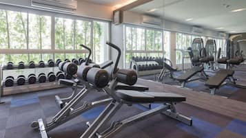 A gym with exercise equipment, dumbbells, and a large mirror.