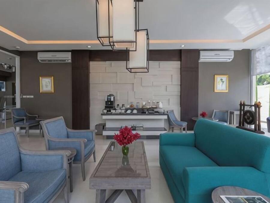 Una sala moderna con un sofá, sillas, una mesa de centro y una cocina al fondo.