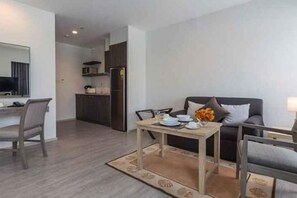 A modern living room with a sofa, dining table, and kitchen area. - Kantary Hotel, Amata Bangpakong (Chon Buri)
