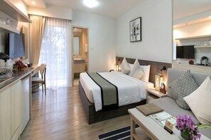 Une chambre d’hôtel équipée d’un lit, d’un bureau, d’une chaise, d’un canapé, d’une télévision et d’une salle de bain.
