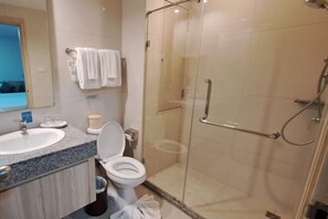 Un baño con ducha de vidrio, lavamanos e inodoro.