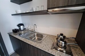 A kitchen with granite countertops, a stainless steel sink, a kettle, and a stove. - Kantary Hotel, Amata Bangpakong (Chon Buri)