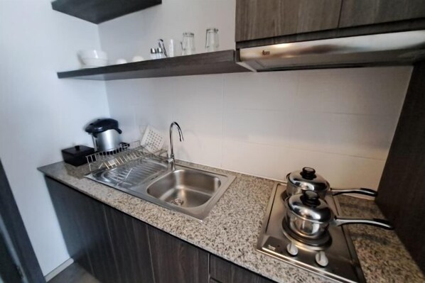 Una cocina con encimeras de granito, un lavamanos de acero inoxidable, una tetera y una estufa.