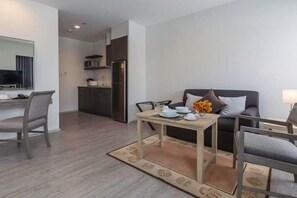 A modern living room with a dining table, sofa, and kitchen area. - Kantary Hotel, Amata Bangpakong (Chon Buri)