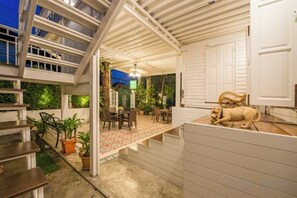 A multi-level outdoor space with a dining area, a staircase, and a dog statue. - Baankachitpan Bangkok Hotel (Bangkok)