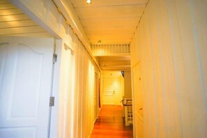 Un couloir étroit, doté d’un plancher en bois et de murs blancs, qui mène à une porte au fond.