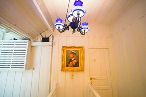 A hallway with a white door, a framed portrait, and a chandelier. - Baankachitpan Bangkok Hotel (Bangkok)