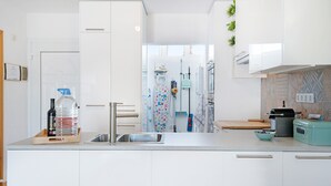 Una cocina moderna con armarios blancos, un lavamanos de acero inoxidable, un dispensador de agua y una pequeña encimera con un tazón.