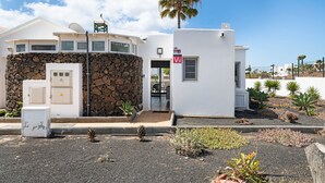Un edificio con fachada de piedra, una estructura pequeña adosada y una palmera.