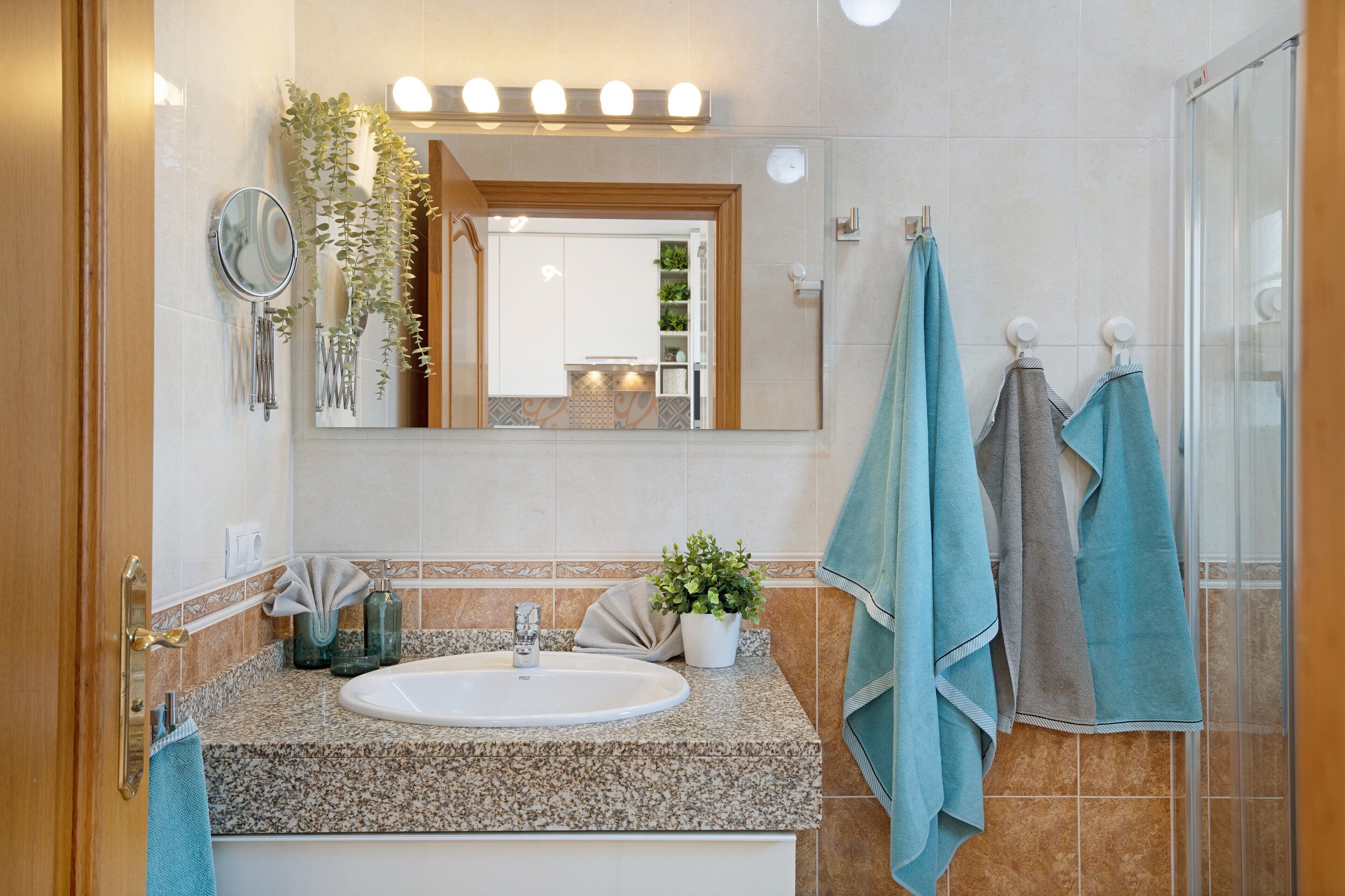 Een badkamer met een wastafel, spiegel, handdoekrek en douche.