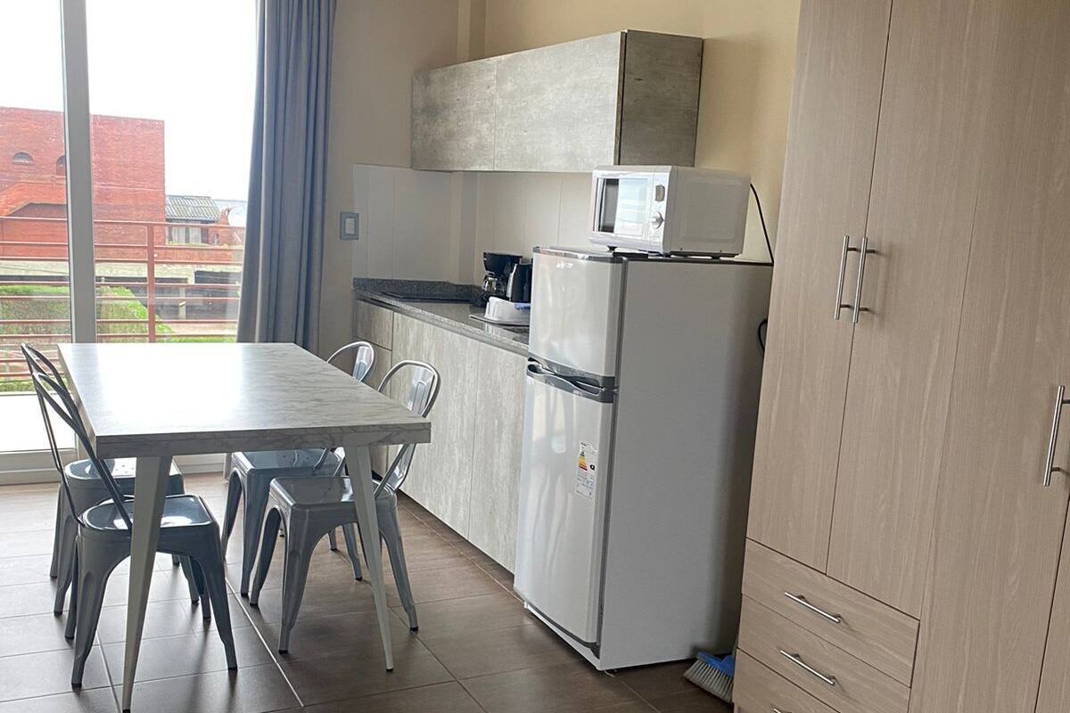 Une cuisine moderne équipée d’une table à manger, de chaises, d’un réfrigérateur et d’un four à micro-ondes.
