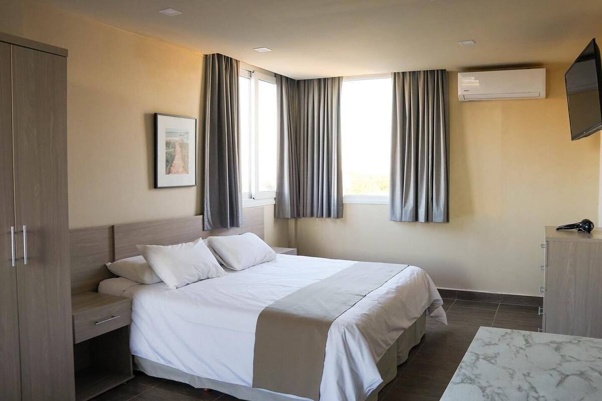 Une chambre d’hôtel équipée d’un lit, d’une armoire, d’un bureau, d’un téléviseur à écran plat et d’un système de climatisation.