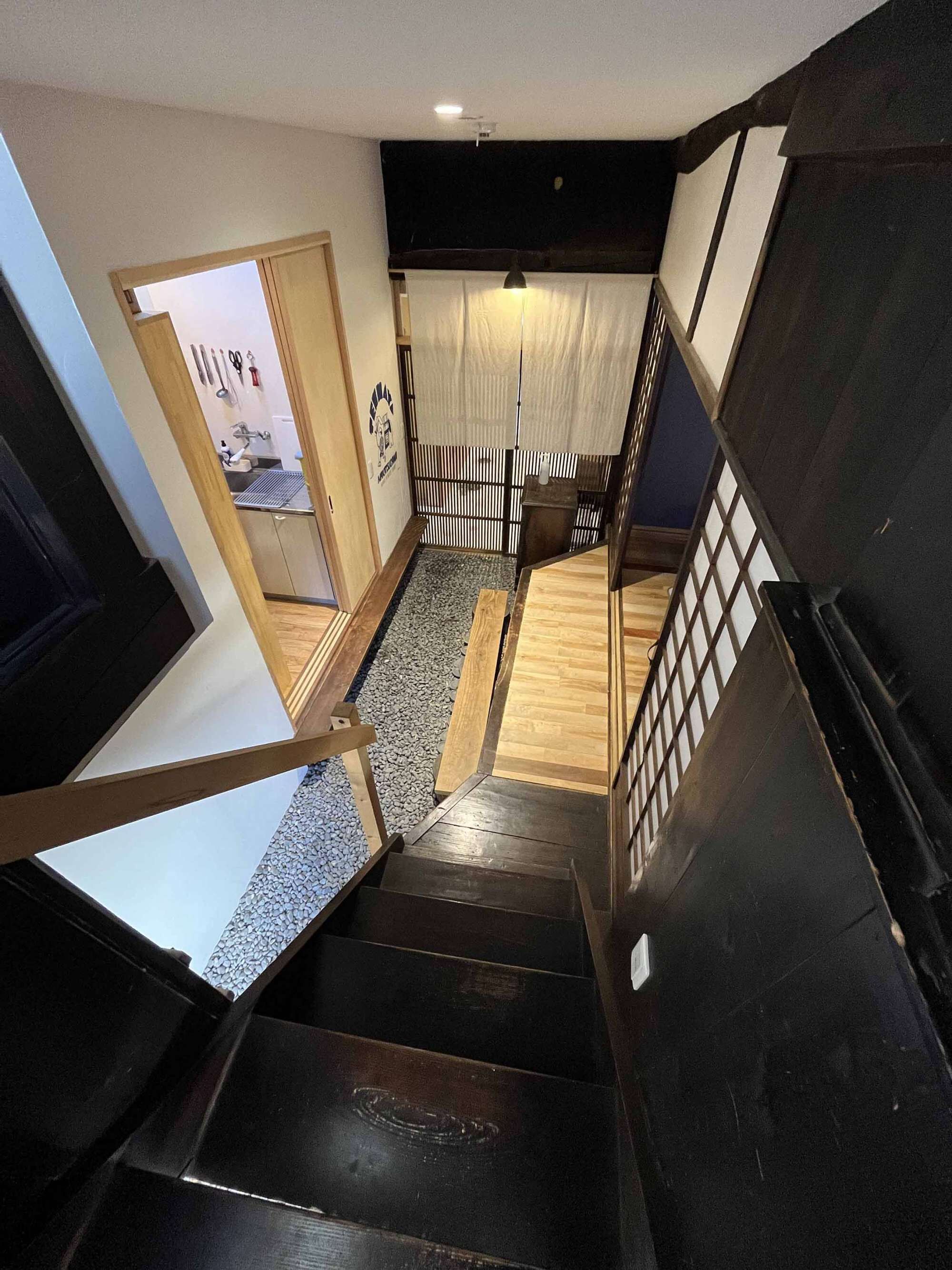 A staircase with a wooden handrail and a black wall on one side.