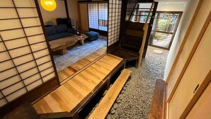 A traditional Japanese-style room with tatami flooring, a low wooden table, and a sofa. - This inn is a renovated old house. (中津川市)
