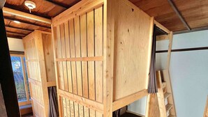 A wooden interior with a sloped ceiling, a built-in bench with a backrest, and a small wooden ladder. - This inn is a renovated old house. (中津川市)