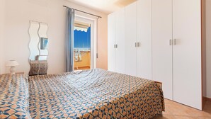A bedroom with a bed, a wardrobe, a mirror, and a view of the beach. - 3896 RSM - Appartamento Iris by Barbarhouse (Manduria)
