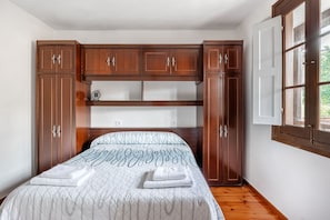 Une chambre à coucher avec un lit, une armoire en bois et une fenêtre.