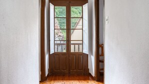 En gang med en trædør, der fører ud til en balkon med udsigt over grøn bevoksning.