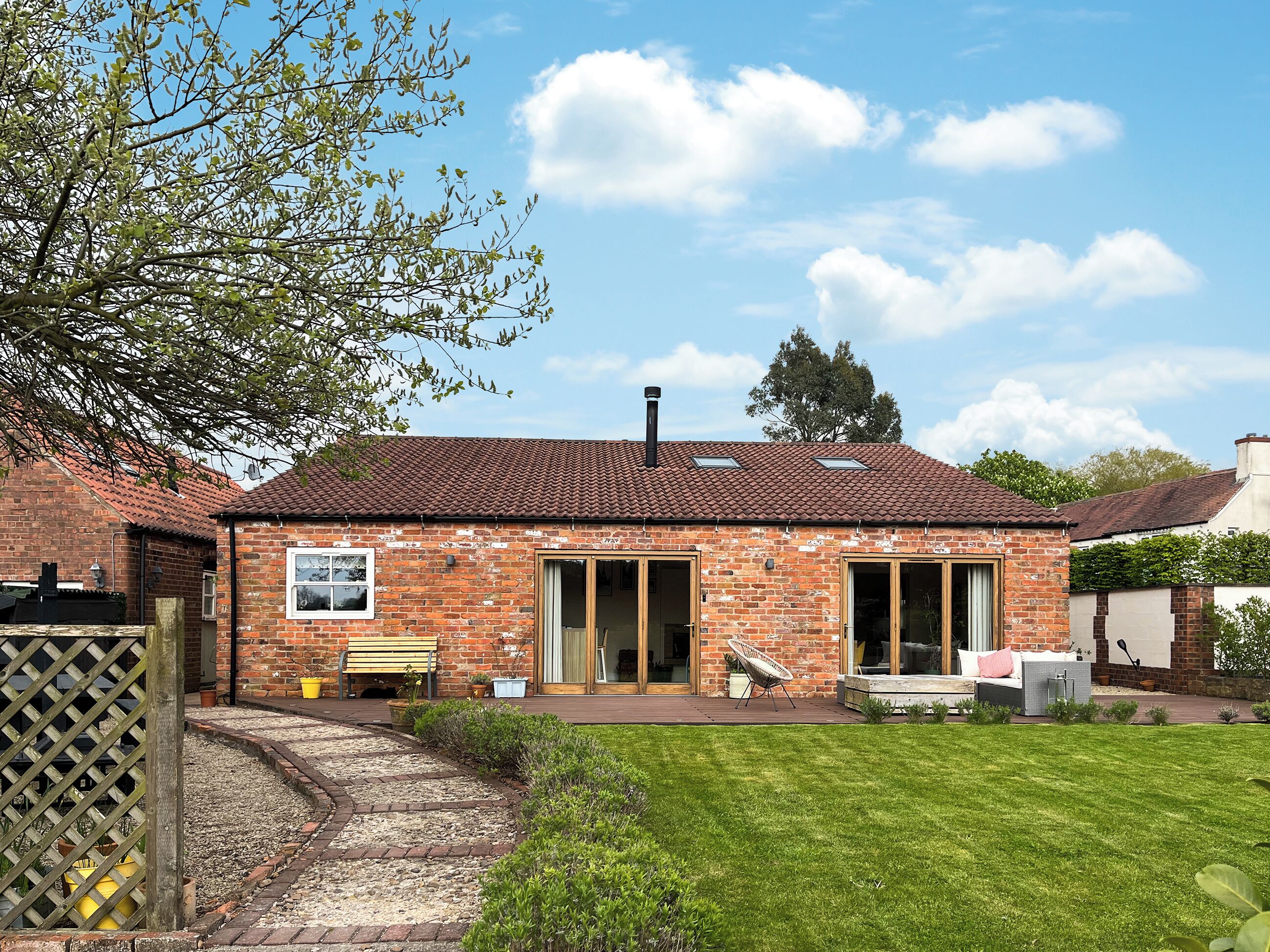 A brick house with a tiled roof, a front porch, and a well-maintained lawn.