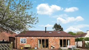 A brick house with a tiled roof, a front porch, and a well-maintained lawn.