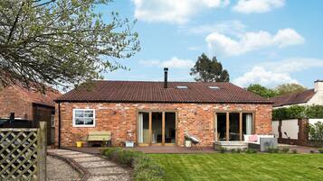 A brick house with a tiled roof, a front porch, and a well-maintained lawn.