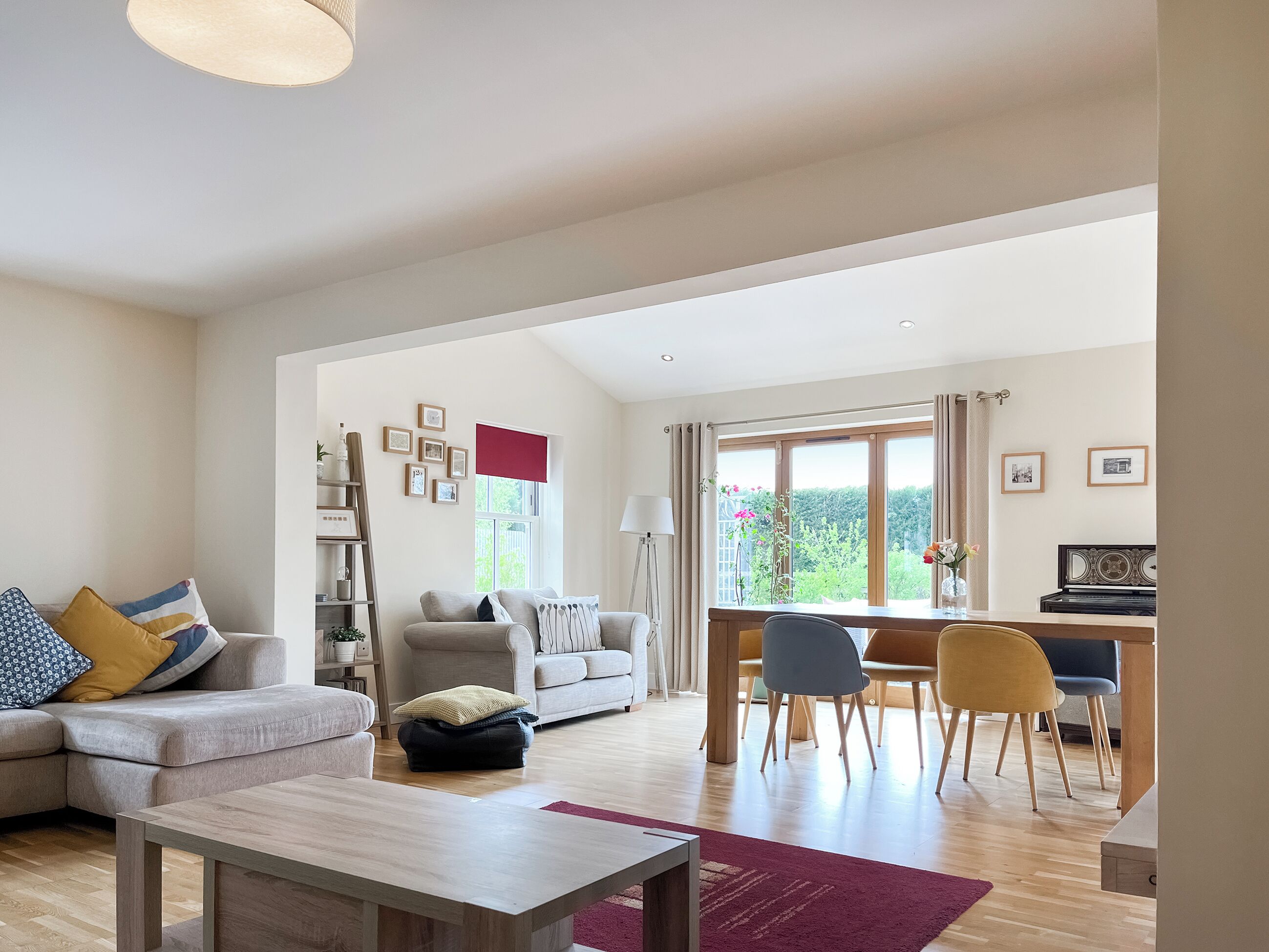 A spacious living room with a sofa, a coffee table, and a dining area with chairs and a piano.