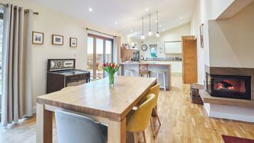 A modern kitchen with a central island, a dining area with a wooden table and chairs, and a fireplace.