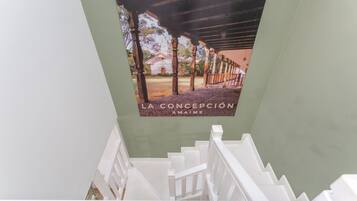 A staircase with white railings leading to a room with a green wall and a poster of a building.