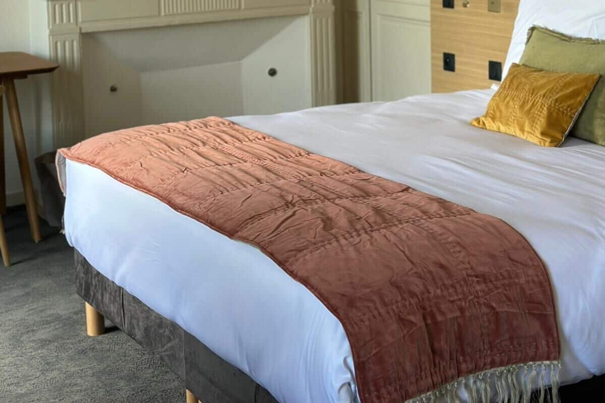 Un dormitorio con cama, cómoda, espejo y lámpara colgante.