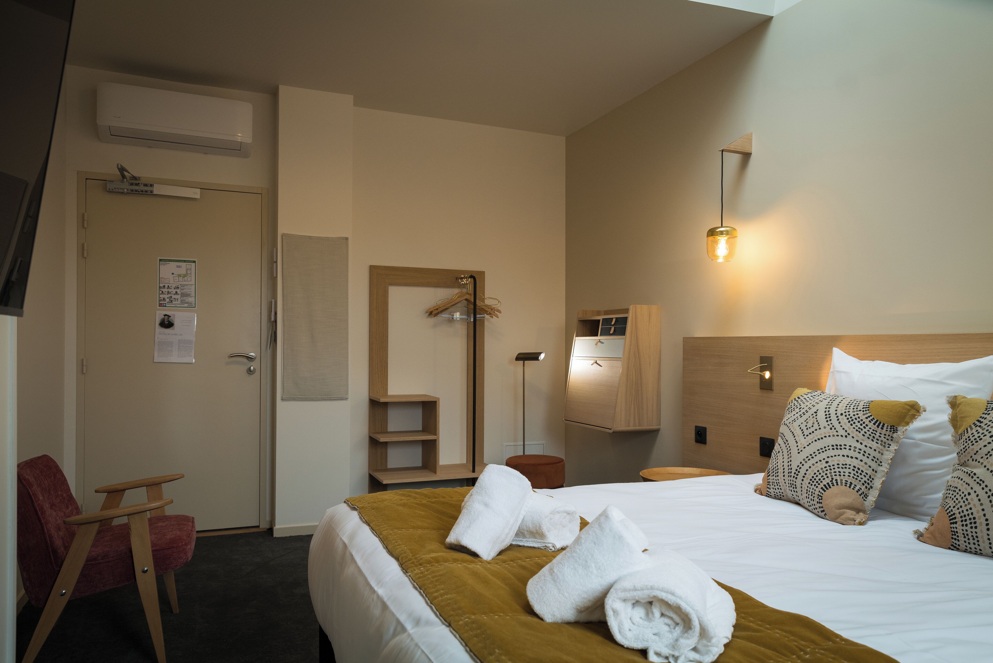 Habitació d'hotel amb llit, una cadira, un armari i un mirall.