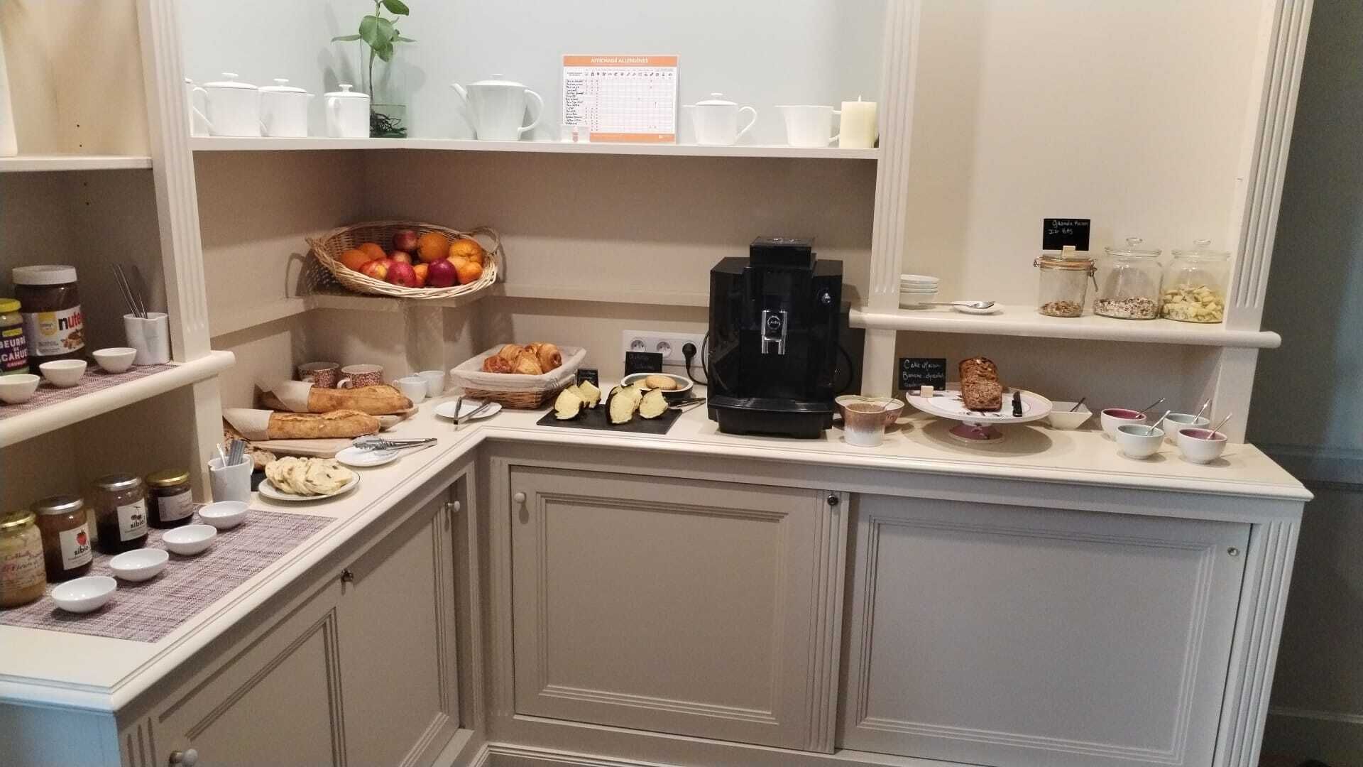 A kitchen with a coffee maker, jars of condiments, and a fruit basket.