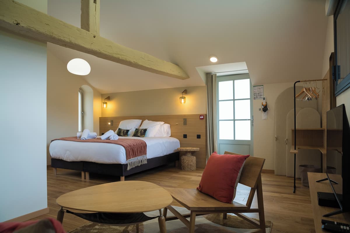 Habitación de hotel con cama, escritorio, silla, mesa y ventana.