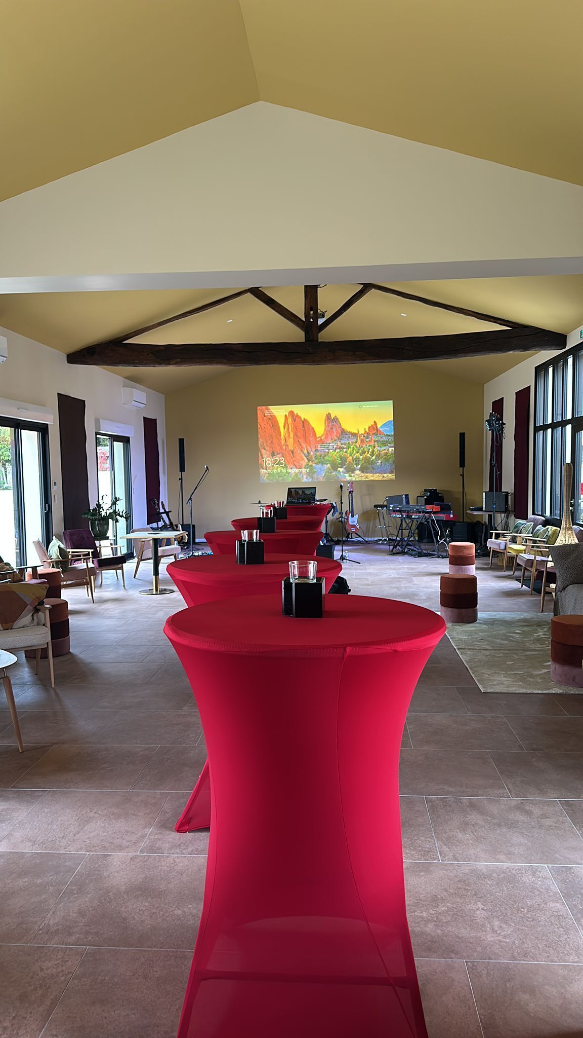 Una habitación amplia con un escenario, mesas rojas y un gran ventanal con vistas al paisaje desértico.