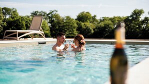 A couple in a swimming pool with a bottle of wine in the foreground. - Domaine de l'Ecorcerie (Liguge)