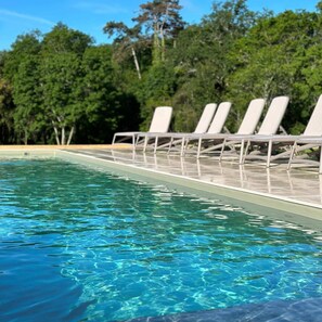 A swimming pool with clear blue water and white lounge chairs along the edge. - Domaine de l'Ecorcerie (Liguge)