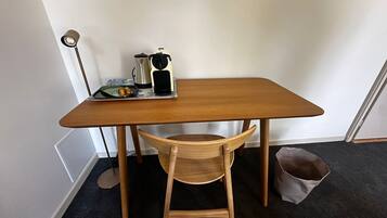 Een houten tafeltje met een stoel, een lamp, een waterkoker en een bord met eten.