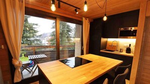 Cocina compacta con encimera de madera, horno empotrado y vistas a una terraza con mobiliario exterior.