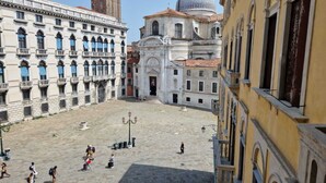 A spacious public square with historic buildings, including a prominent church with a dome, and a building with blue-striped awnings. - 2 bedroom apartment in venice (Venezia)