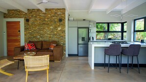 Una cocina moderna con pared de piedra, un refrigerador empotrado y una zona de bar con dos taburetes.