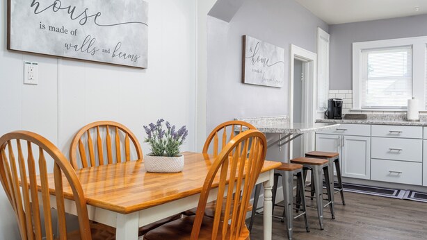 A modern kitchen with white cabinets, a wooden dining table, and two bar stools. - 3 bed/1 bath lower unit conveniently located in Lakeside. (Muskegon)