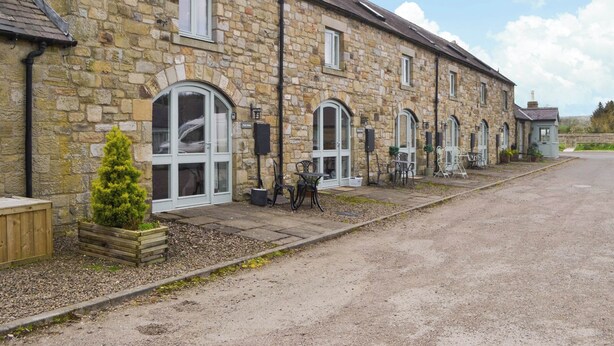 A stone building with arched windows and a gravel driveway. - 2 bedroom accommodation in Netherton Near Rothbury (Netherton Near Rothbury)