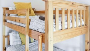 A bunk bed with wooden railings and a mattress with a plaid blanket. - 2 bedroom accommodation in Netherton Near Rothbury (Netherton Near Rothbury)