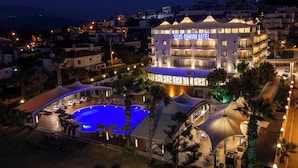 A hotel with a swimming pool, outdoor seating, and a well-lit facade. - Sisus Marina Hotel (Cesme)