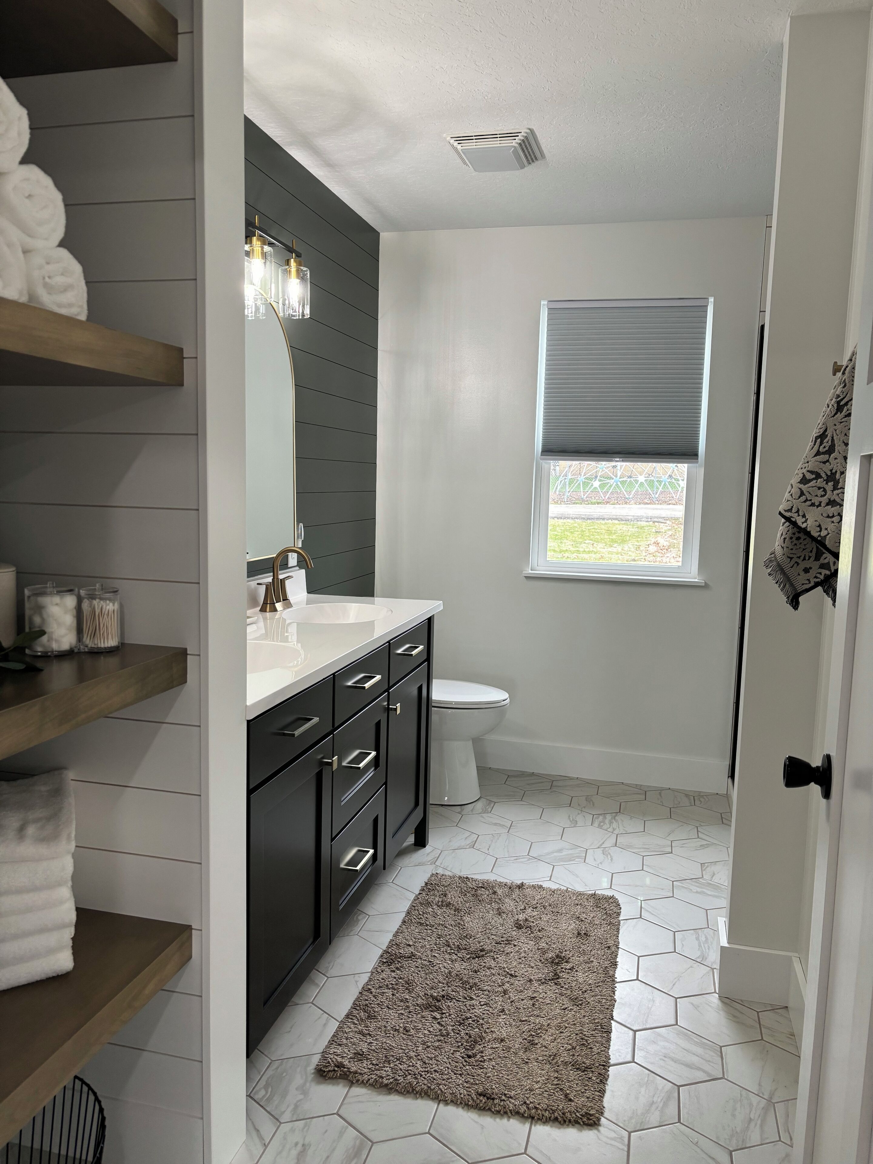 A modern bathroom with a white toilet, dark wooden vanity, and a large mirror.