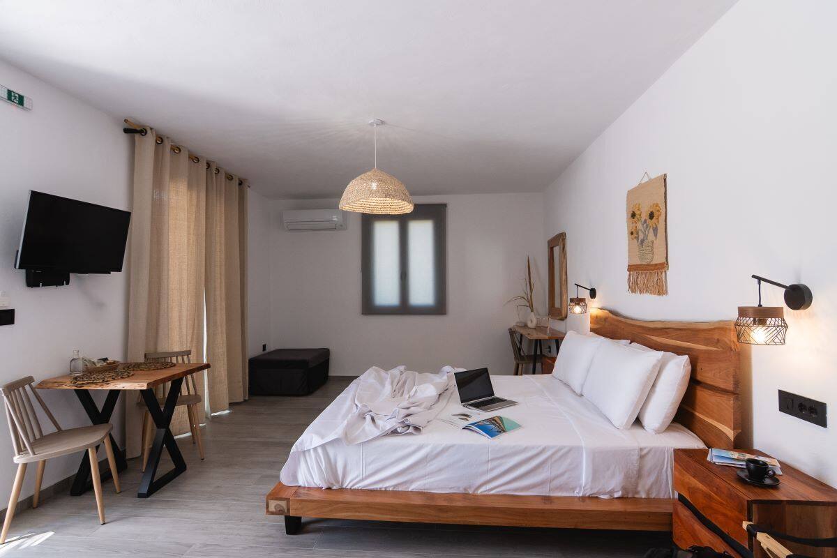 A modern bedroom with a wooden bed, a desk, a television, and a hanging light fixture.