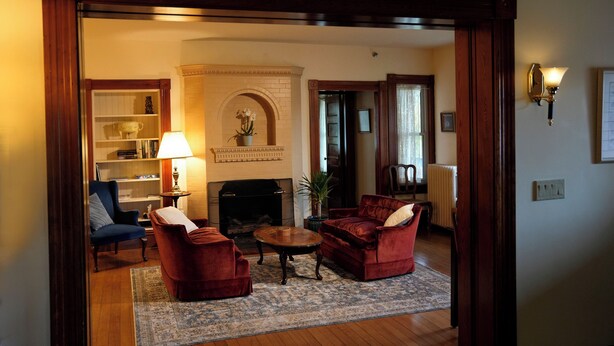 Una sala de estar con chimenea, un sillón azul, un sofá rojo y una mesa de centro.