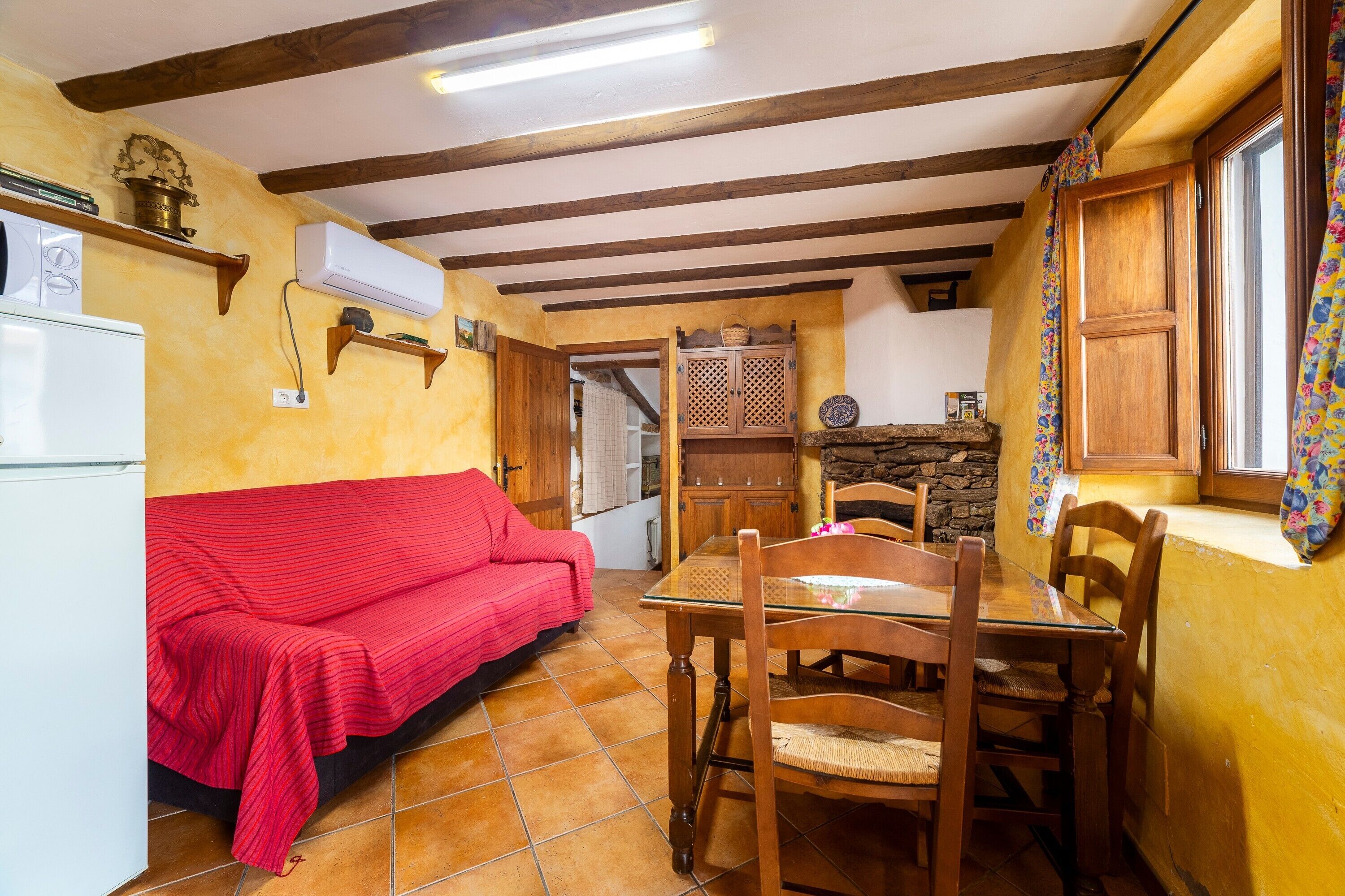 Una cocina con un sofá rojo, una mesa de comedor de madera y sillas.