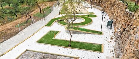Ein angelegter Garten mit geometrischen Mustern, einer Steinmauer und einem Weg.