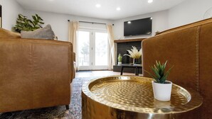 Ein Wohnzimmer mit einer Couch, einem Couchtisch, einem Fernseher und einem Kamin.